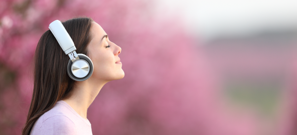 野外でヘットフォンで音楽を聴いている女性