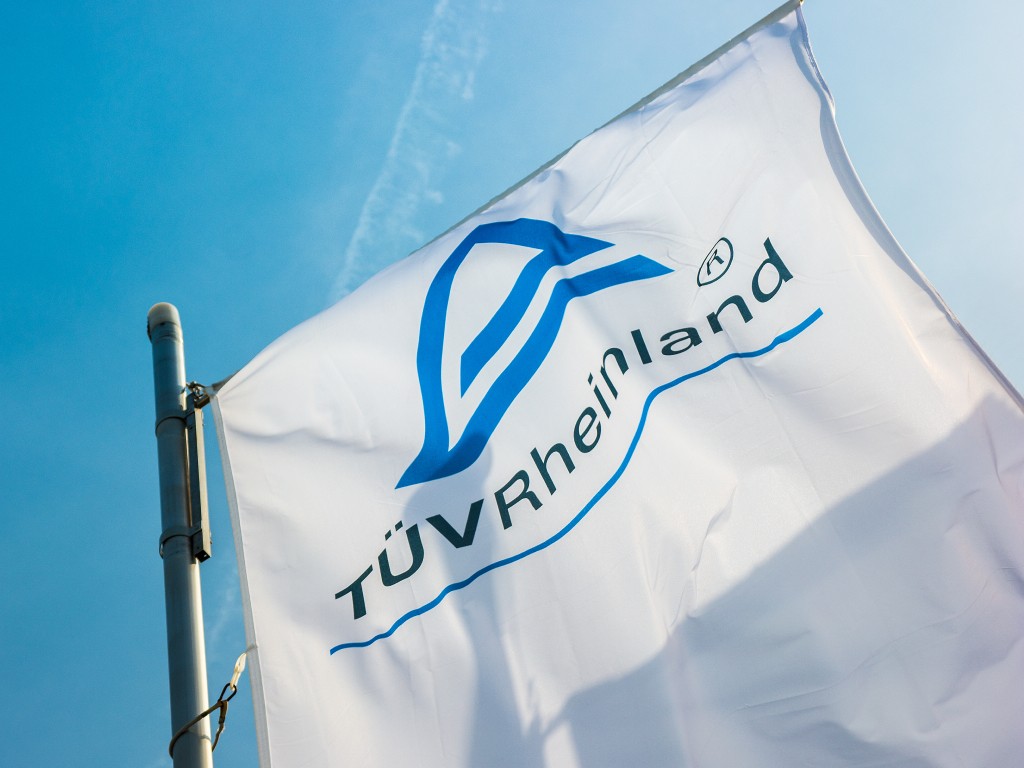 Sonnenbeschienene Flagge mit TÜV Rheinland Logo. 