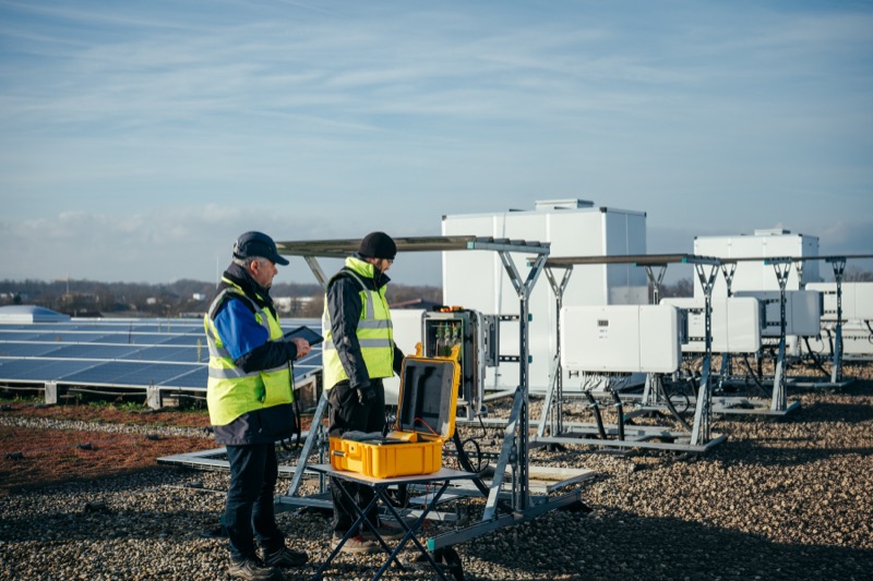 Zwei Ingenieure in Sicherheitswesten bei der Inspektion einer Solarpark-Anlage